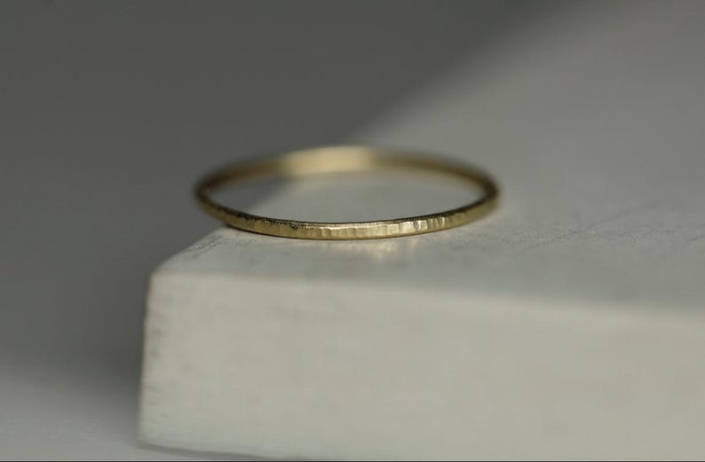 May include: A thin gold band ring with a hammered texture.