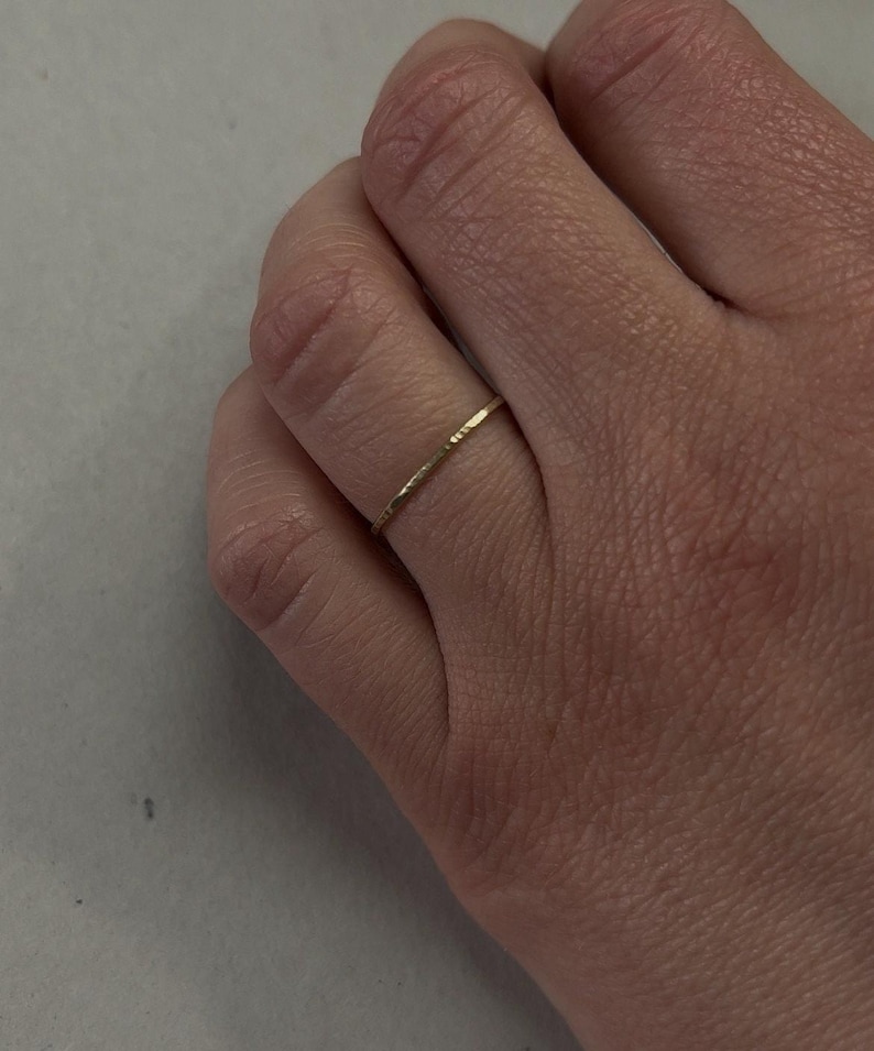 May include: A thin gold band ring with a hammered texture.