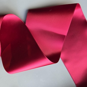 May include: A roll of deep red satin ribbon. The ribbon is smooth and shiny.