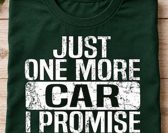 May include: A dark green short-sleeved t-shirt featuring white distressed-style text that reads JUST ONE MORE CAR I PROMISE, with the word CAR highlighted inside a white rectangular box across the center of the chest area.