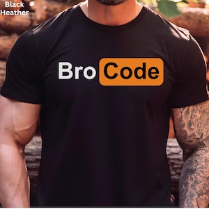 May include: Black t-shirt with the text "Bro Code" in white letters and an orange rectangle. The shirt is made of a dark fabric and has short sleeves. The words are centered on the front of the shirt.