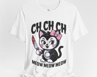 May include: White t-shirt featuring a cartoon cat with a pink bow, holding a bloody knife. The shirt has the text "CH CH CH" above the cat and "MEOW MEOW MEOW" below it. The cat is black and white with pink cheeks.