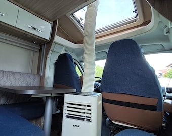 May include: A white portable air conditioner with the brand name elit printed on the front, positioned inside a vehicle cabin. A flexible white exhaust hose extends from the top of the unit upward through an open rectangular roof vent.