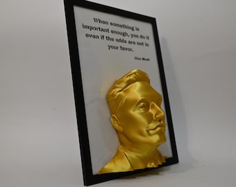 May include: A gold-colored 3D bust of a man in a black frame. The bust is set against a white background. The quote "When something is important enough, you do it even if the odds are not in your favor." is printed in black text below the bust. The quote is attributed to "Elon Musk".