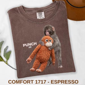 Baby monkey punch shirt featuring macaque hugging plush toy on black t-shirt