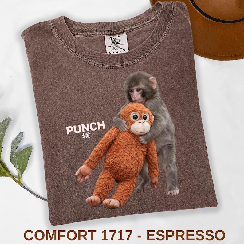 Baby monkey punch shirt featuring macaque hugging plush toy on black t-shirt