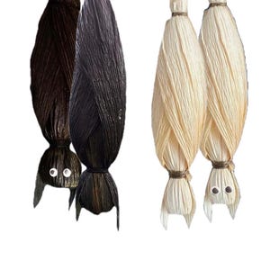 Könnte beinhalten: Zwei schwarze und zwei weiße Fledermäuse aus Maiskolben, die an einer Schnur hängen. Die Fledermäuse haben Glitz Augen.