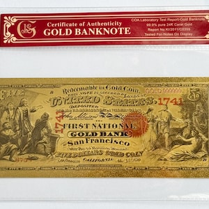 May include: A gold-colored $5 banknote with the text "United States, 1741" and "First National Gold Bank, San Francisco". The note is framed in a clear plastic sleeve with a red and gold certificate of authenticity.