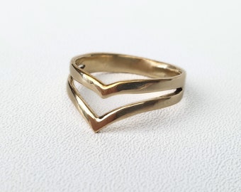 May include: A gold-coloured double V-shaped ring.
