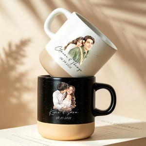 Puede incluir: Dos tazas de cerámica apiladas verticalmente. La taza superior es blanca con una base color canela, con una ilustración en acuarela de una pareja y el texto "Claire & Things 06.18.2026". La taza inferior es negra con base canela, mostrando una pareja y "Kevin & Sara 08.15.2026".