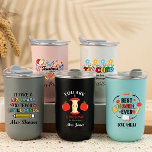 May include: Five insulated tumblers with lids, each with a unique design for teachers. The tumblers are in pink, white, grey, black, and teal. Each has a teacher-themed graphic and text, such as "Best Teacher Ever". The tumblers are approximately 12 cm tall.
