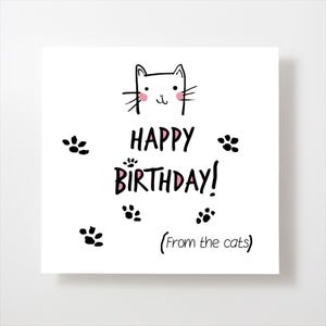 May include: A white card with a black and white illustration of a cat's head with pink cheeks. The card says "Happy Birthday! (From the cats)" and has black paw prints around the text.