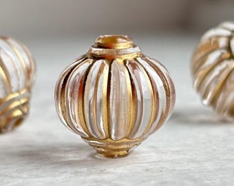 May include: Three round, ribbed beads featuring clear glass segments alternating with metallic gold vertical stripes. Each bead has a central hole and a slightly flattened top and bottom, creating a symmetrical, pumpkin-like shape.