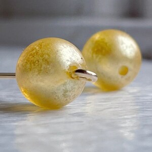 May include: A pair of yellow pearl earrings with gold-toned metal findings.