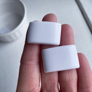 May include: Two white rectangular ceramic tiles.