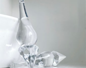May include: Two clear glass crystal ornaments with a teardrop shape and a pointed diamond base.