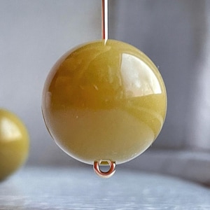 May include: A single, round, olive green bead with a silver loop attached. The bead is smooth and shiny.