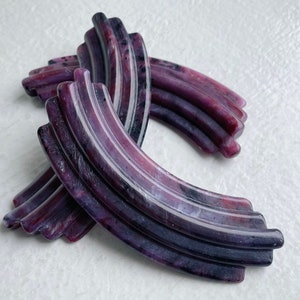 May include: Three purple and black hair clips with a wavy, striped design.