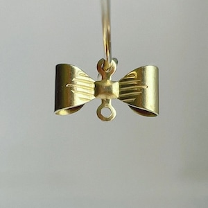 May include: Gold-toned bow-shaped earring with a loop for hanging.