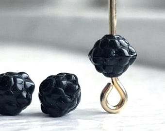 May include: Three black glass beads in the shape of blackberries. The beads are strung on a gold wire with a gold hook at the end.