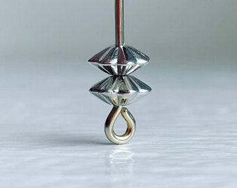 Pode incluir: Conta de metal prateada com um design em forma de diamante e um pequeno gancho na parte inferior.