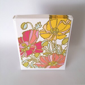 May include: A stack of blank greeting cards with a floral design featuring pink, yellow, and white flowers on a white background.