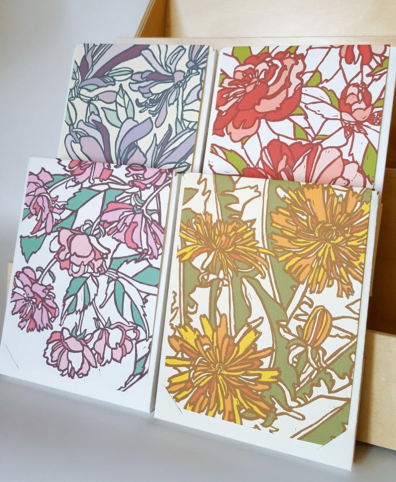May include: Four cards with floral designs. The cards feature different flowers, including pink, red, yellow, and green flowers. The cards are all white with a white border.
