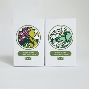 May include: Two white boxes of mini notes. Each box features a circular floral design in a white circle. One has pink and yellow flowers, the other has white and green flowers. Each box reads "8 MINI NOTES 2 DESIGNS | 4 EACH".