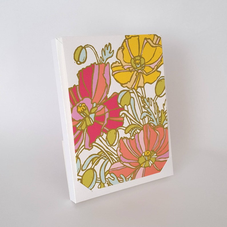 May include: A white card with a floral design featuring pink, yellow, and orange poppies with gold accents.