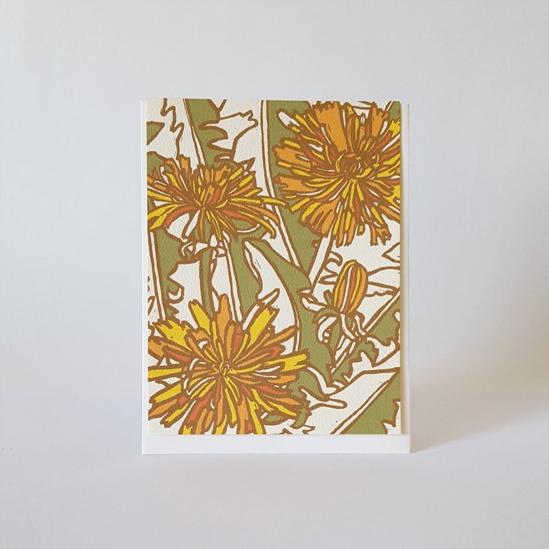 May include: A card with a floral design featuring yellow and orange dandelions on a green background.