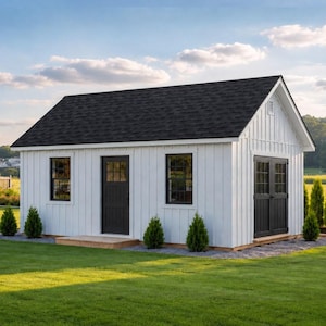 May include: A small, white shed with a black roof and black doors and windows. The shed is surrounded by green grass and small evergreen trees. The sky is blue with a few clouds.