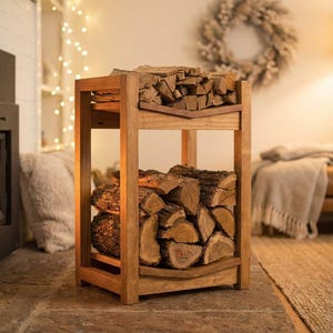 May include: A two-tiered, wooden firewood rack filled with cut logs. The rack is made of light-colored wood and is rectangular. The logs are stacked neatly on each level. The background includes a fireplace, a wreath, and string lights.