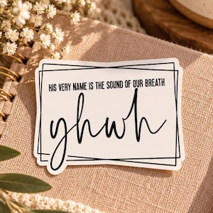 May include: A rectangular white sticker with black text that reads HIS VERY NAME IS THE SOUND OF OUR BREATH and yhwh in a cursive script. The sticker features a black geometric border consisting of overlapping thin rectangular frames.