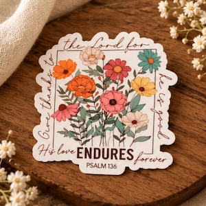 May include: A die-cut sticker featuring a bouquet of colorful flowers in shades of orange, pink, yellow, and teal. The text reads: Give thanks to the Lord for he is good. His love ENDURES forever. PSALM 136, framed in a thin brown border.