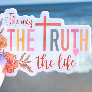 May include: A white sticker with the text "The way THE TRUTH the life" in colorful letters. A small pink heart is next to the word "TRUTH". The sticker has a floral design with orange and pink flowers.
