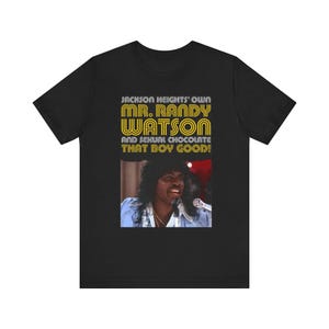 May include: Black t-shirt featuring a graphic of Mr. Randy Watson with the text "Jackson Heights' Own Mr. Randy Watson and Sexual Chocolate That Boy Good!" The image shows a man with a microphone.