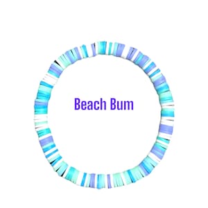Op de afbeelding: Een kleurrijke armband gemaakt van platte, ronde kralen in tinten blauw, turquoise en wit. De tekst "Beach Bum" staat in paars weergegeven. De armband is cirkelvormig en staat tegen een witte achtergrond.