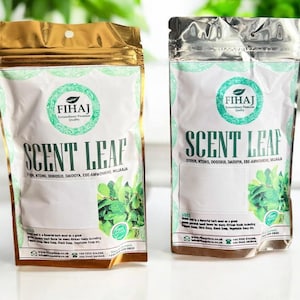 May include: Two pouches of FIHAJ Scent Leaf. The pouches are white with a green and gold design. The text "SCENT LEAF" is prominently displayed. The pouches contain a green leafy herb. The text "FIHAJ Extraordinary Premium Quality" is also visible.