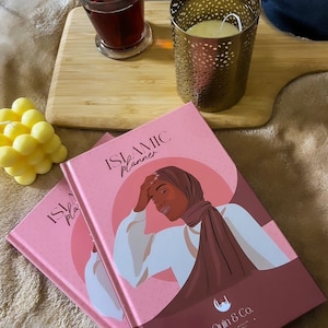 Peut inclure: Deux livres de planification islamique rose et marron avec le texte "Islamic Planner" et "Oyin & Co." sur la couverture. La couverture présente une illustration numérique d'une femme portant un hijab.