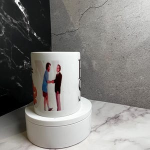 May include: White ceramic mug with a vintage image of two people shaking hands. The mug has the words "Best Of" printed on it. The mug is displayed on a white, round platform.
