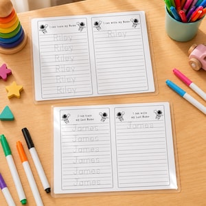 May include: Two laminated educational practice sheets featuring astronaut illustrations. The top sheet displays the name Riley with tracing lines and blank lines. The bottom sheet displays the name James with tracing lines and blank lines for writing.