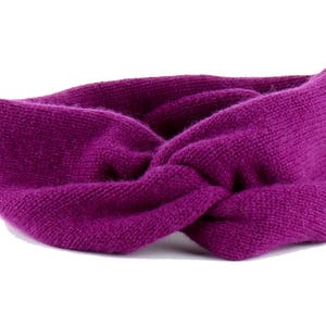 May include: A purple knitted headband with a twisted design.