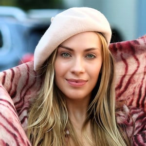 The model is wearing a rose colored wool beret and a tiger print scarf.