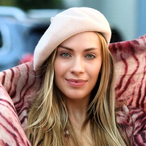 The model is wearing a rose colored wool beret and a tiger print scarf.