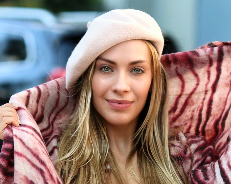 The model is wearing a rose colored wool beret and a tiger print scarf.