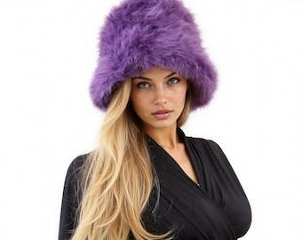 May include: A vibrant purple bucket hat crafted from thick, long-pile faux fur material. The hat features a rounded crown and a short, downward-sloping brim, providing a textured and voluminous appearance with deep violet tones throughout the fabric.