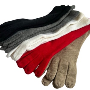 May include: A stack of five pairs of long fingerless gloves in various colors, including black, gray, white, red, and beige.