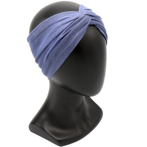May include: A periwinkle blue headband with a twisted knot design. The fabric has a subtle, textured appearance. The headband is displayed on a black mannequin head, showcasing its shape and style. This accessory is designed for hair styling.