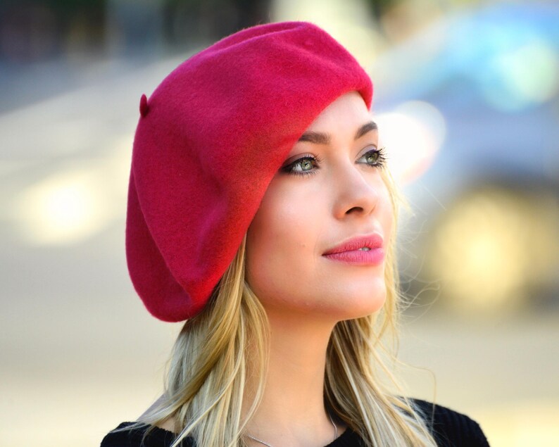 May include: A woman wearing a bright red beret. The beret is made of felt and has a simple design.