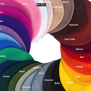 May include: A color chart of 20 different felt beret hats. The hats are arranged in a circle, with the colors ranging from pink to black. The colors are labeled with their names, such as "Pink", "Blush", "Off White", "Oatmeal", "Mocha", "Caffe latte", "Espresso", "Terra Cotta", "Maroon", "Red", "Orange", "Gold", "Lemon", "Black", "Charcoal", "Celadon", "Rock", "Concrete", "Green", "Hunter", "Navy", "Emerald", "Blue", "Sky", "Lavender", "Purple", and "Magenta".
